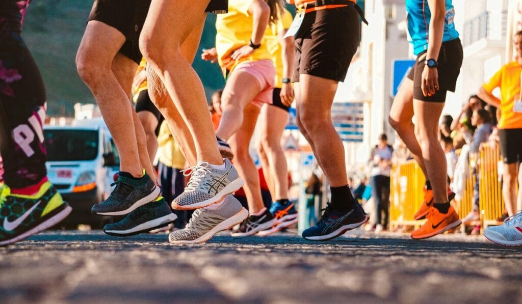 A group of runners wearing colorful running shoes participating in a race on a sunny day.