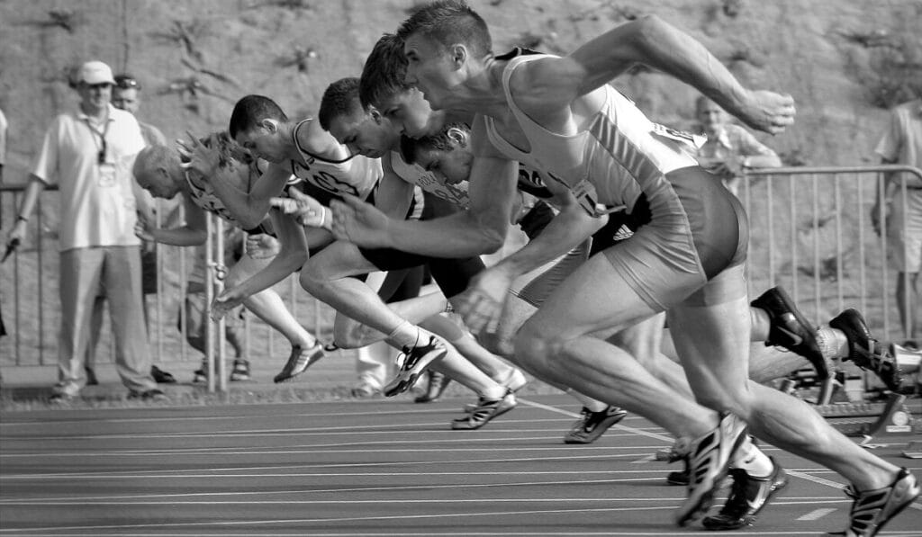 Group of male sprinters starting a race on an outdoor track.