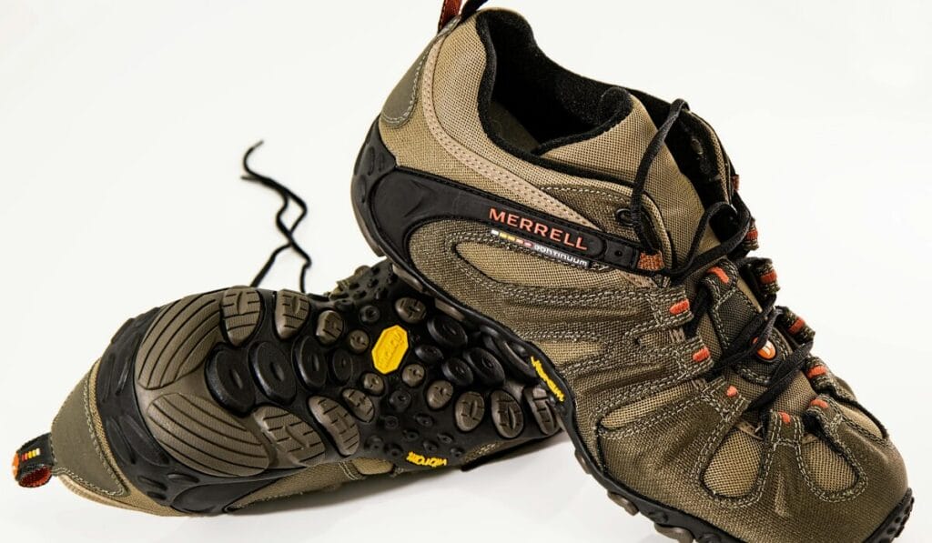 Pair of Merrell trail shoes in brown and black with rugged Vibram outsoles for hiking and outdoor terrain.