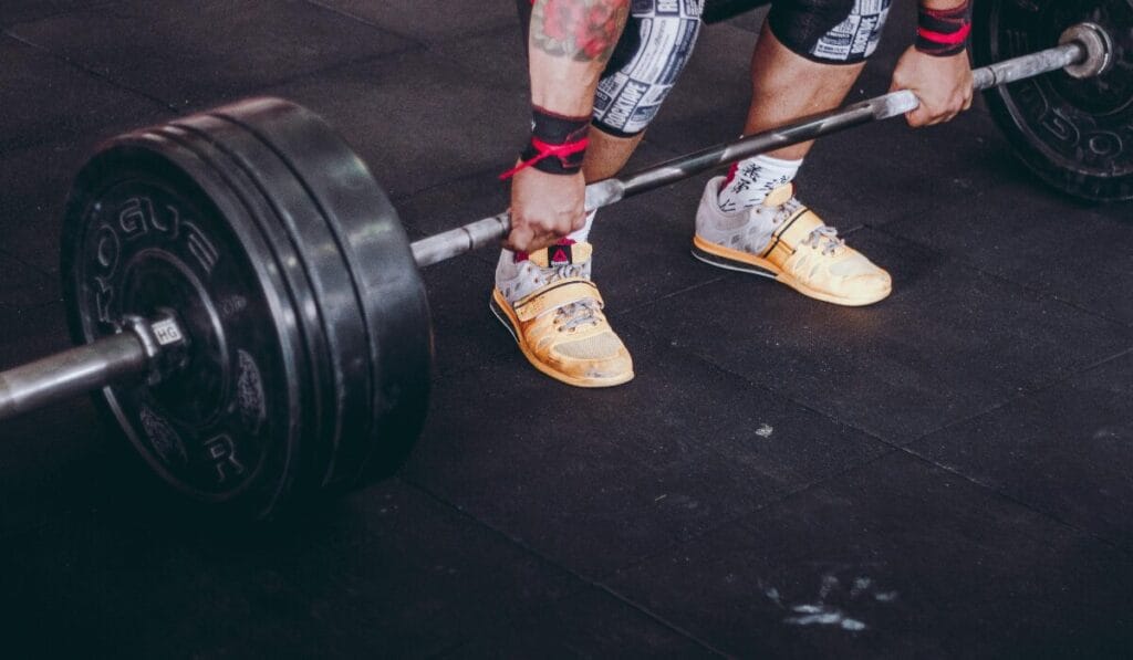 Athlete wearing yellow training shoes performing a heavy deadlift in a gym